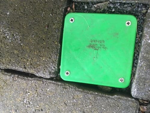 Green earth rod inspection box flush in concrete with "DANGER EARTH ROD" label